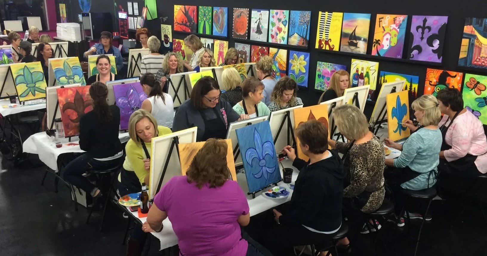 Large indoor group paint party with canvases on easels