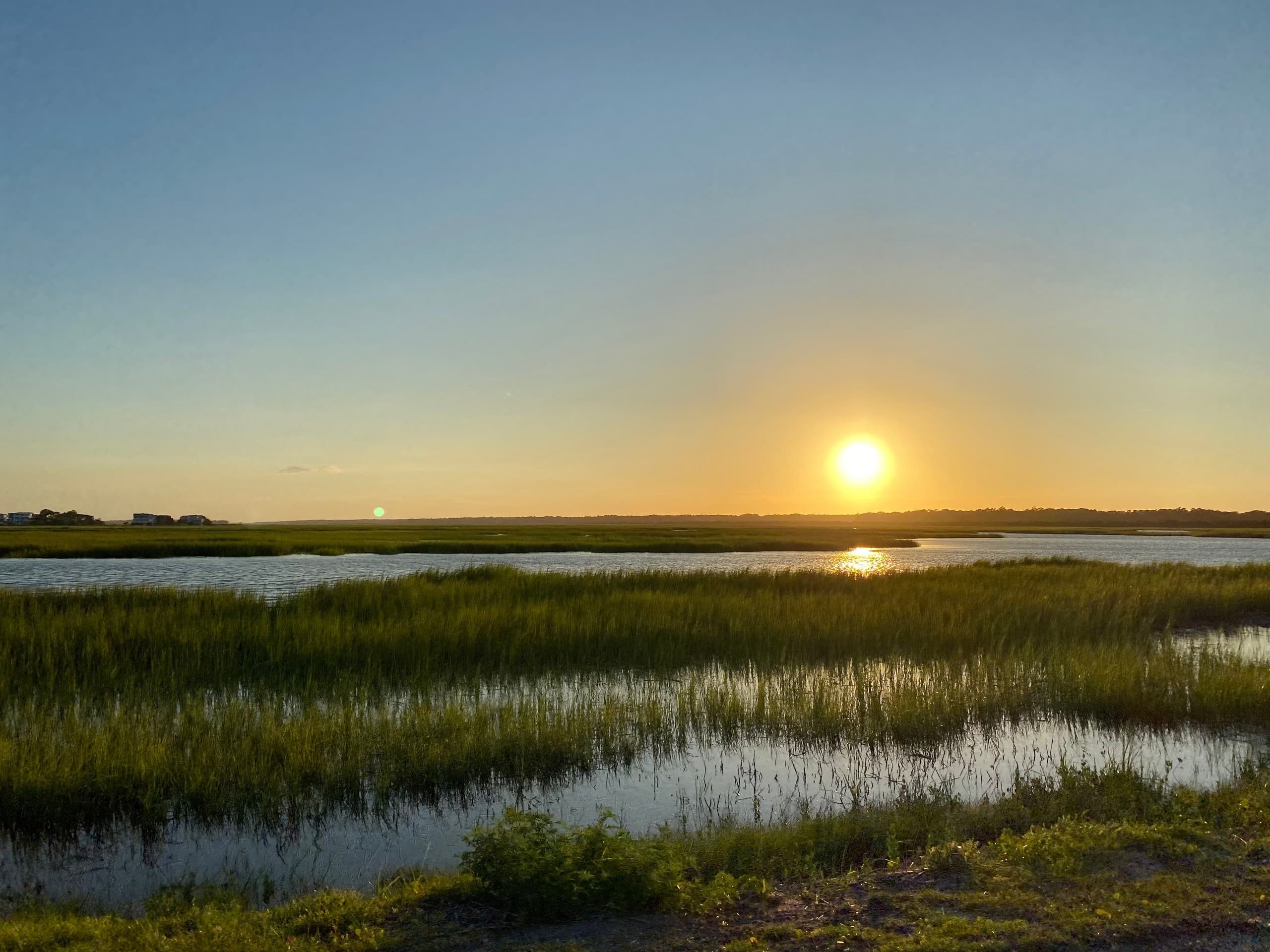 Sunset over salt marsh with glowing sky and distant horizon