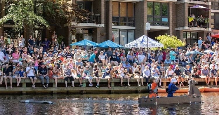 Crowd watching waterfront boat race at community pier