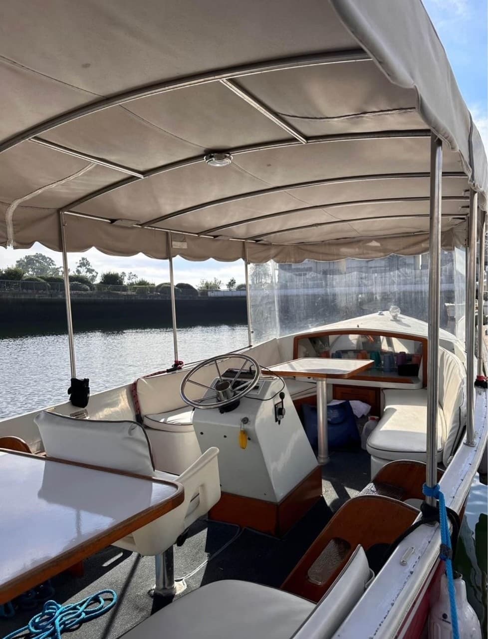 Covered boat interior with helm and seating on calm canal