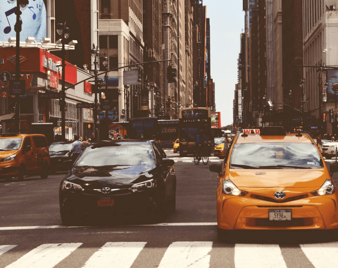 Downtown city street with taxis crossing busy urban intersection