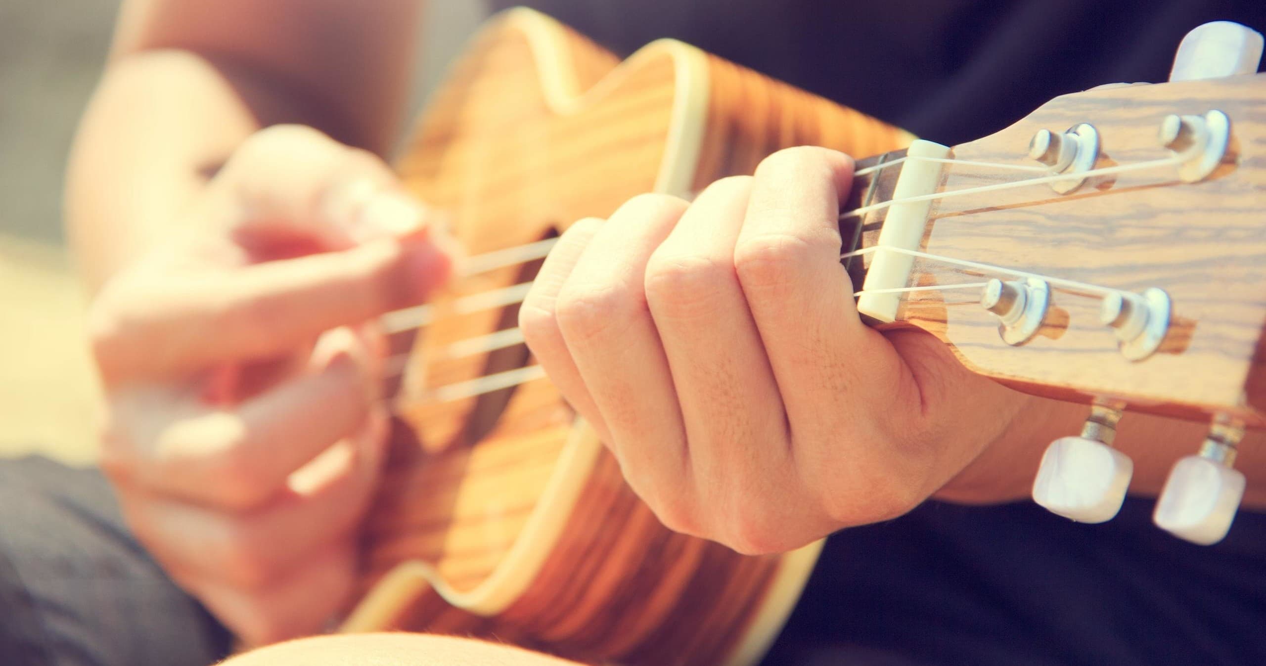 Close-up of hands strumming ukulele at beachfront luau