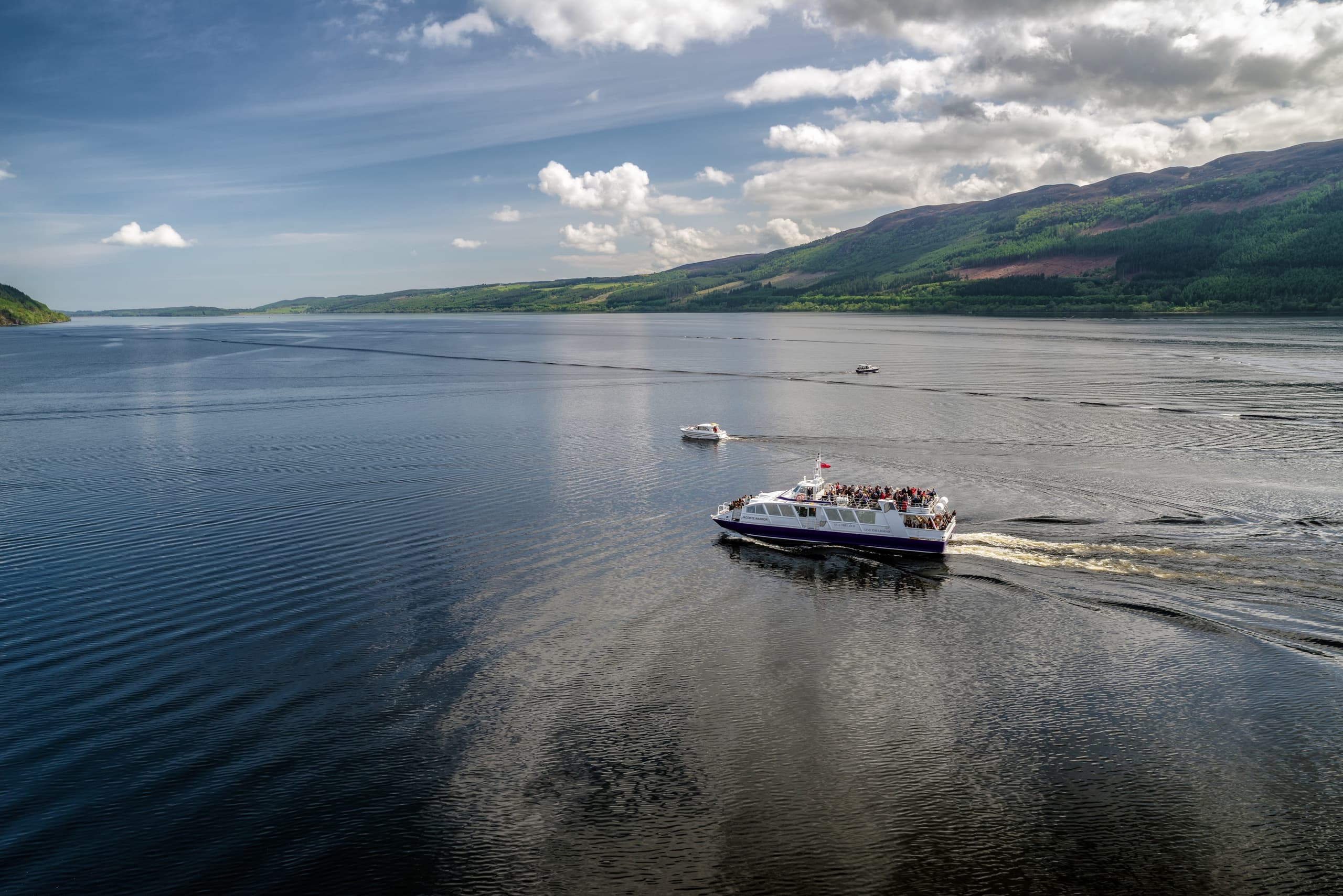 Tour boat cruising across misty loch with mountains in background