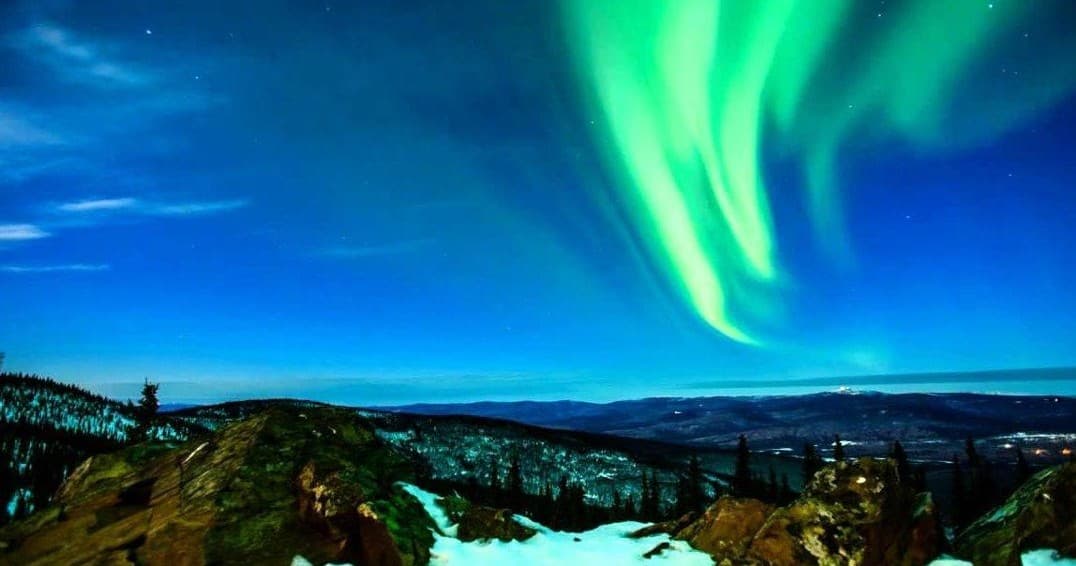 Aurora borealis dancing over Alaskan landscape at night
