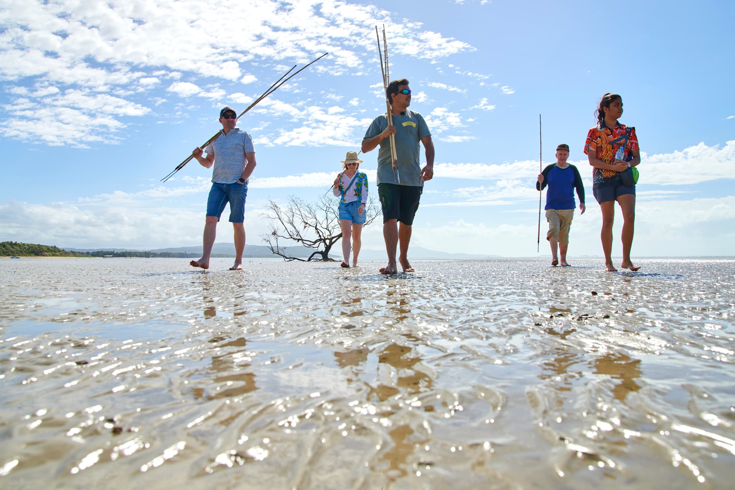 Group walking on wet sand beach at low tide, coastal walk