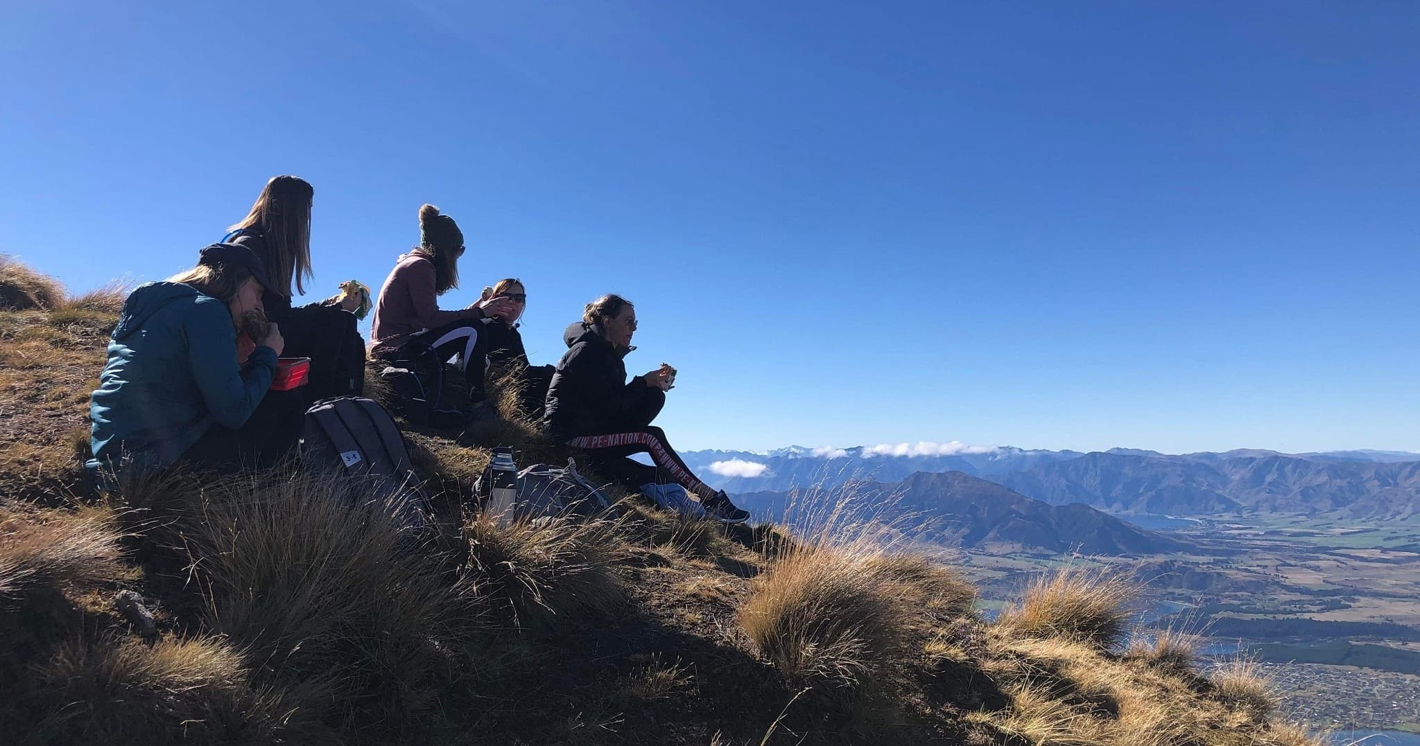Hikers resting on alpine ridge overlooking valley and mountains