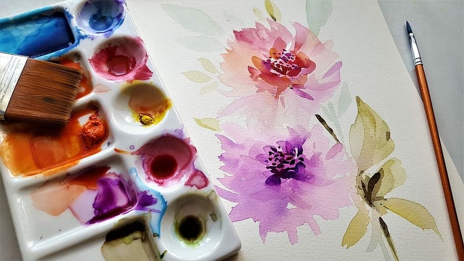 Artist painting watercolor flowers on studio desk indoors