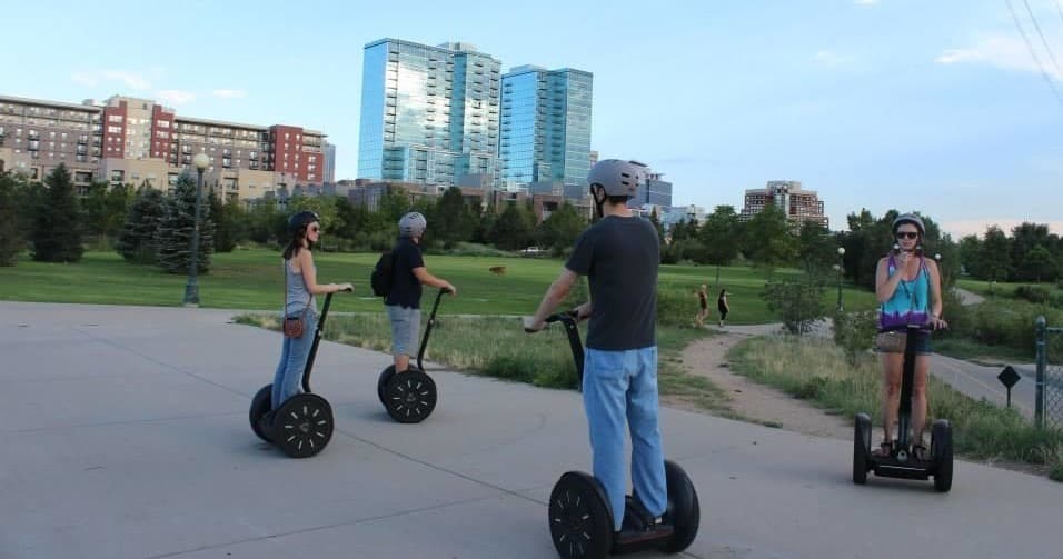 Segway riders touring urban park with city skyline backdrop