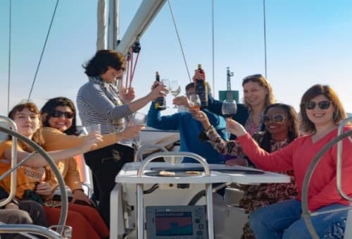 Friends toasting aboard sailboat enjoying coastal day cruise