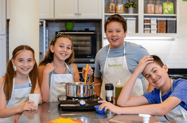 Kids cooking on stovetop during hands-on family cooking class