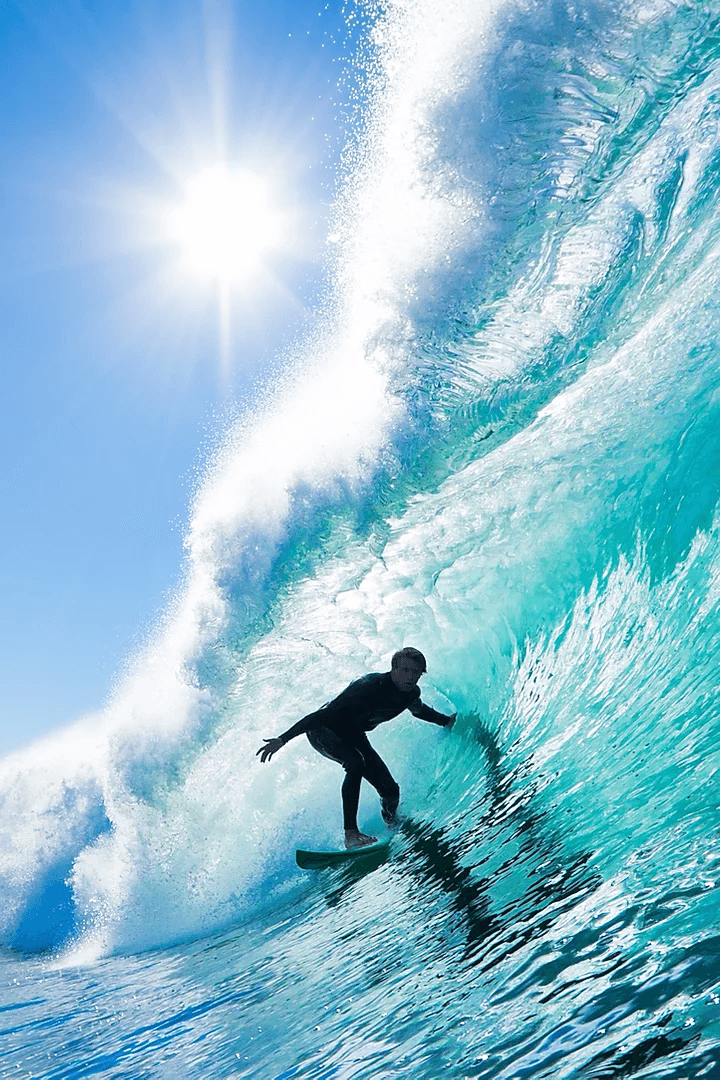 Surfer carving inside a towering turquoise wave near reef
