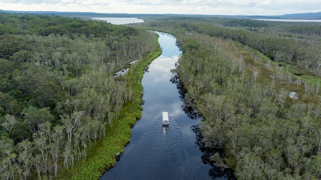 Aerial boat cruising winding Everglades river, wetlands vista