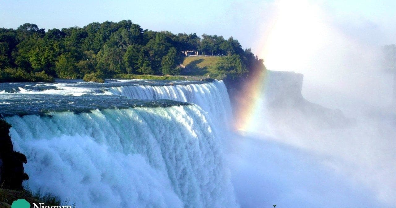 Niagara Falls edge with rainbow over roaring waterfall