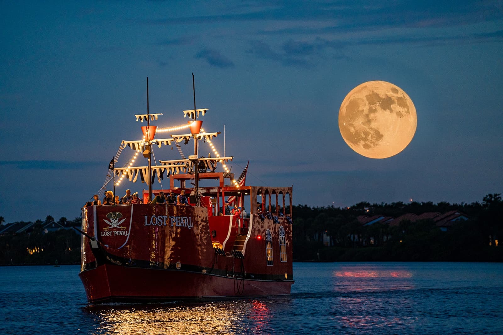 Pirate ship cruising under full moon on Tampa Bay at night