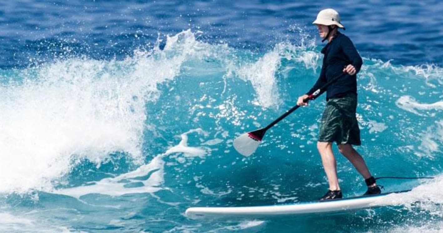 Standup paddler carving through surf with dynamic ocean spray Kona