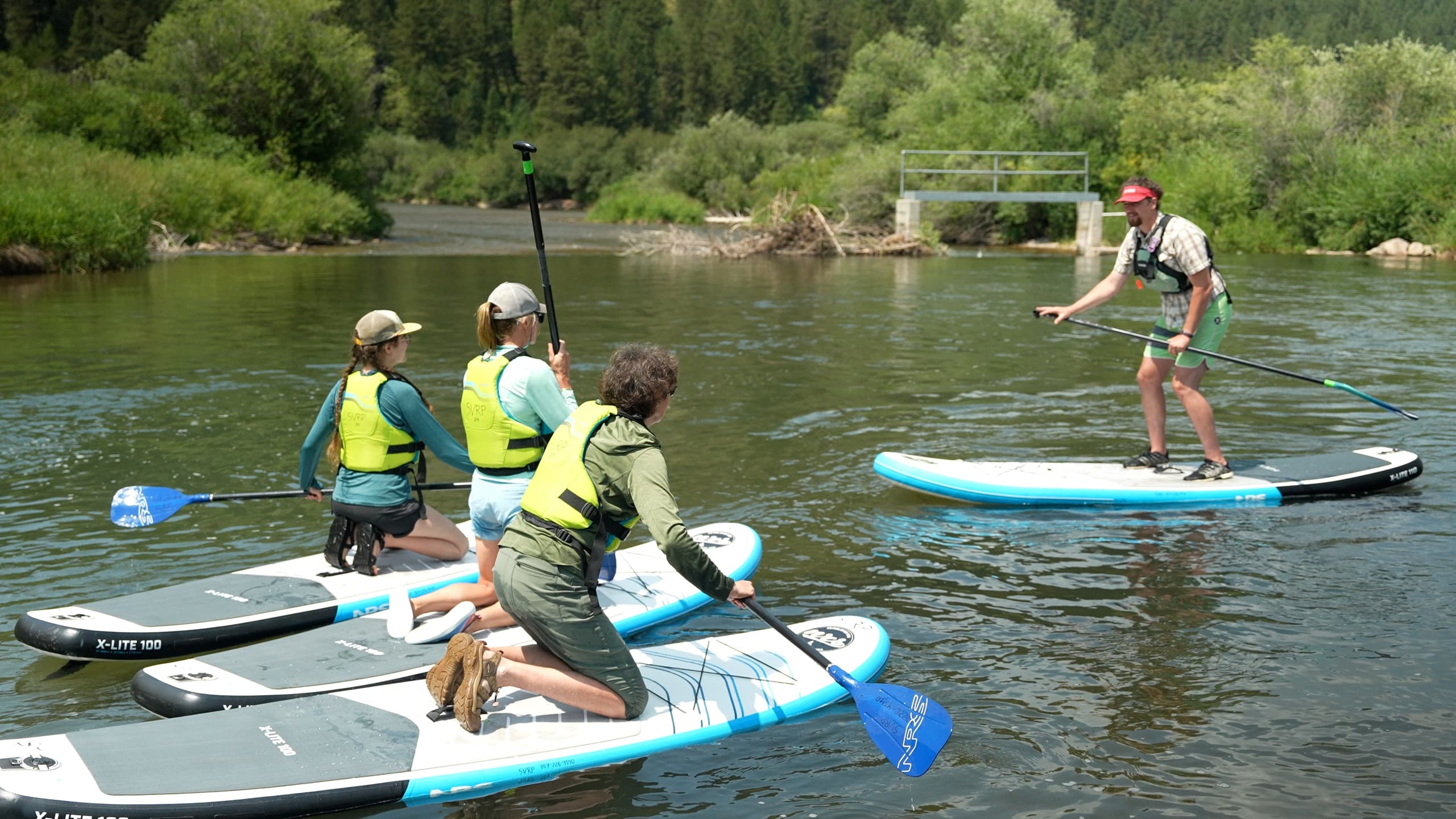 Paddleboarders practicing paddling techniques on peaceful river