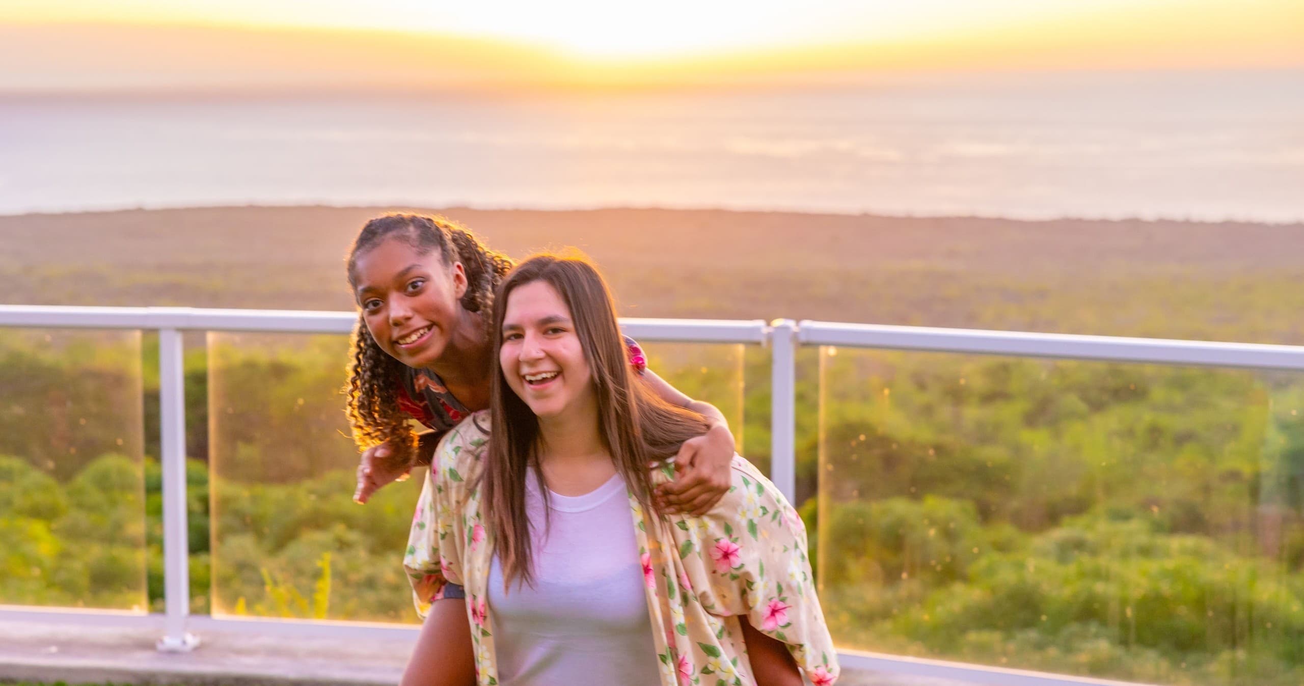 Friends posing on coastal overlook with sunset view in Hawaii