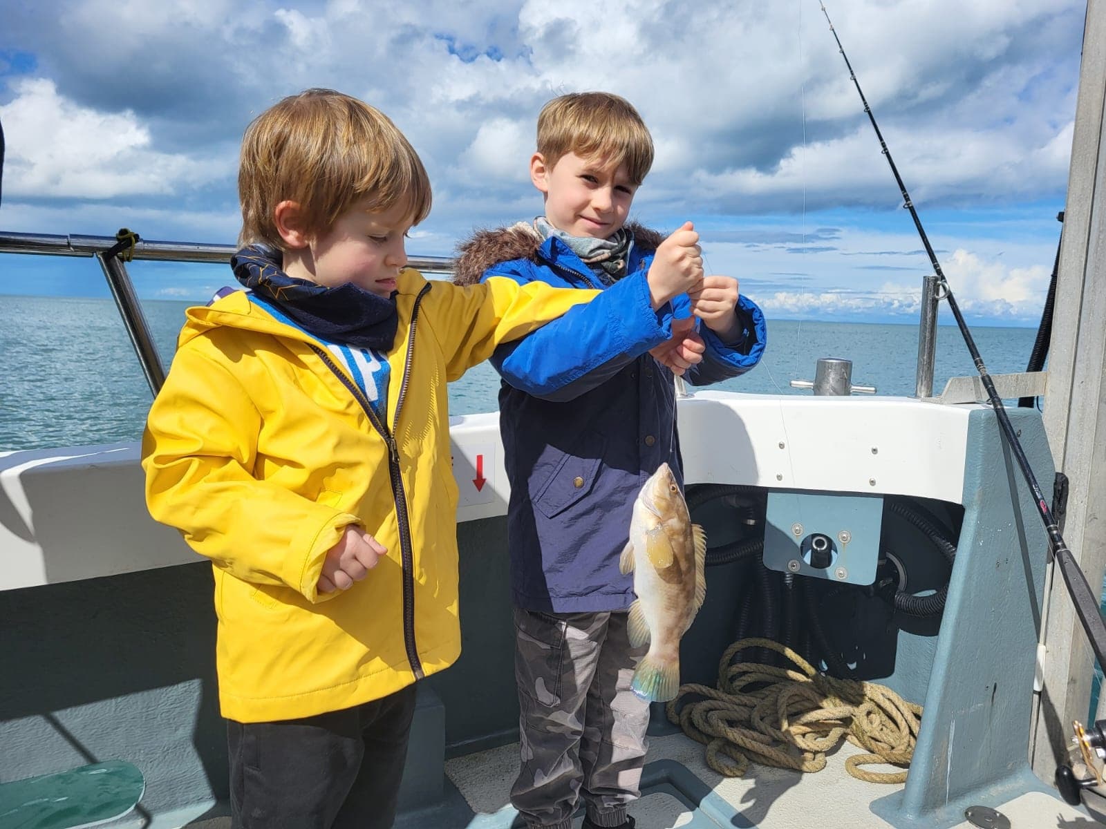 Children fishing on charter boat holding up their catch