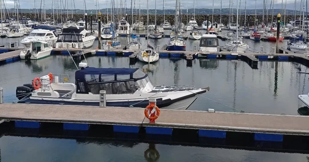 Charter motorboat moored at marina with yachts in coastal harbor