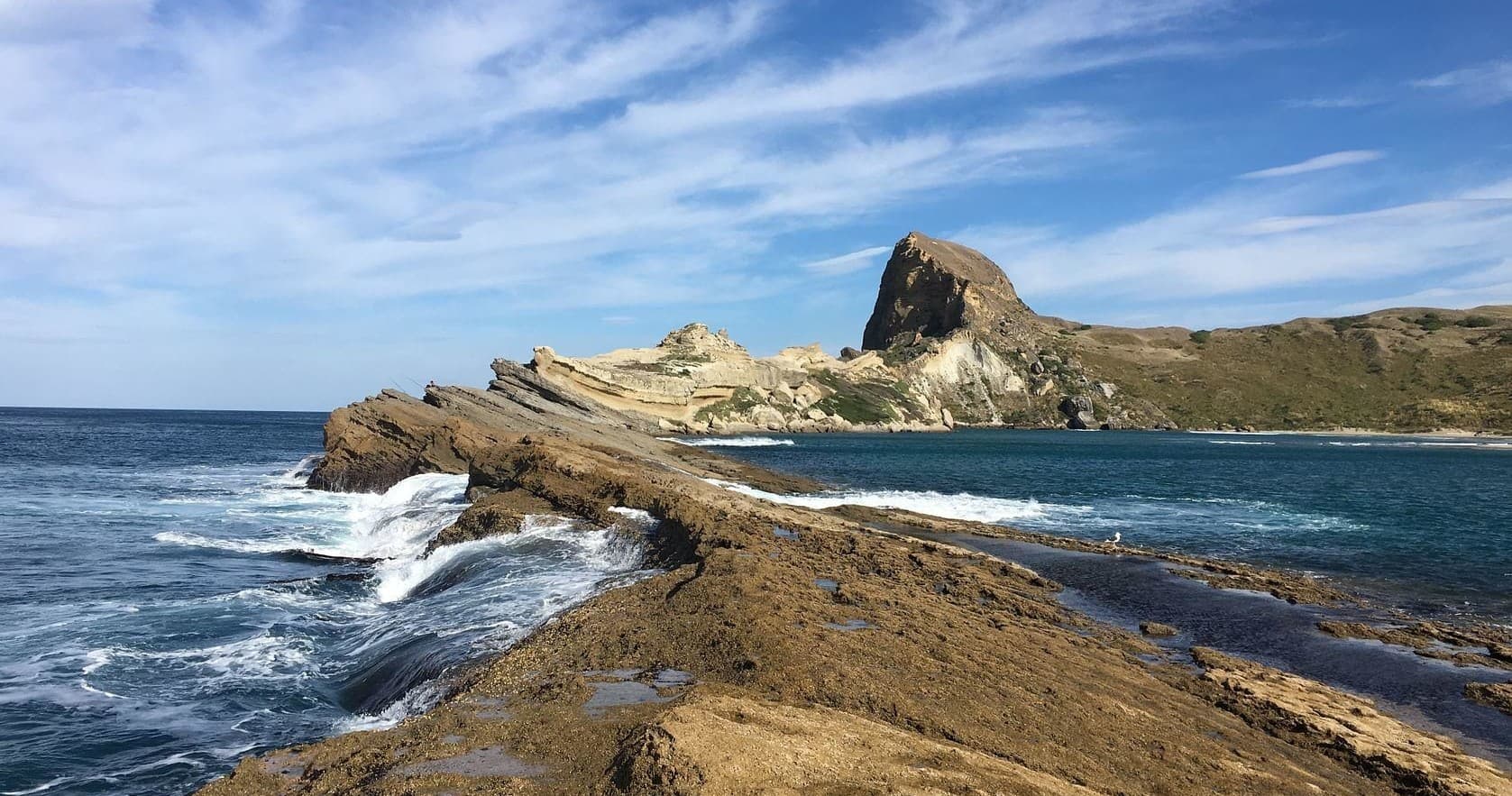 Scenic rocky coastal headland with waves and blue sky