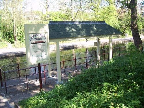 Small riverside boarding shelter on shaded canal towpath