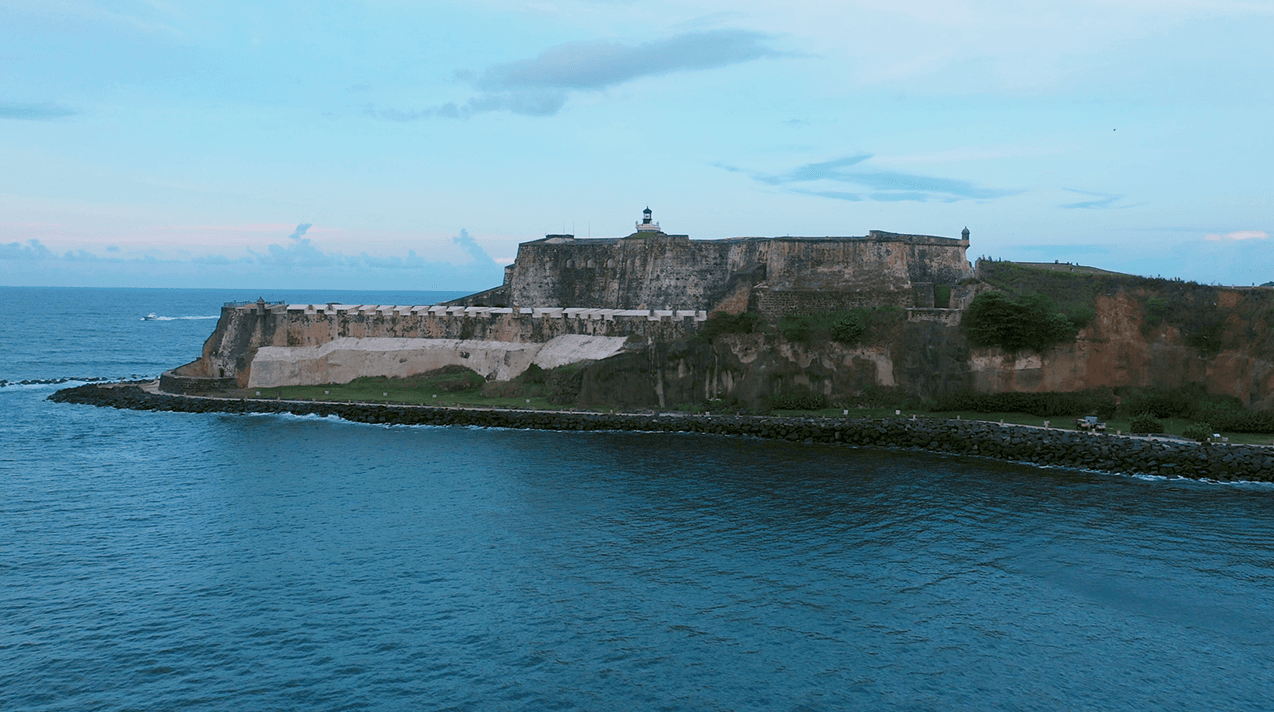 Historic seaside fort on rocky coast at sunset, scenic harbor view