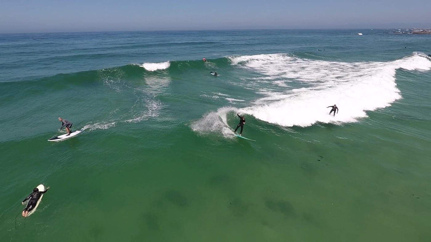 Aerial view of surfers paddling and catching waves in ocean