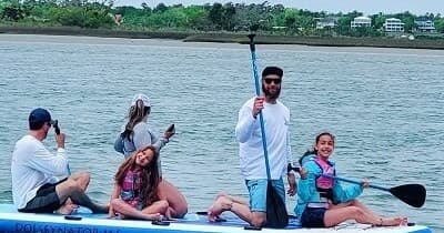 Group paddleboarding on calm bay waters with coastal backdrop