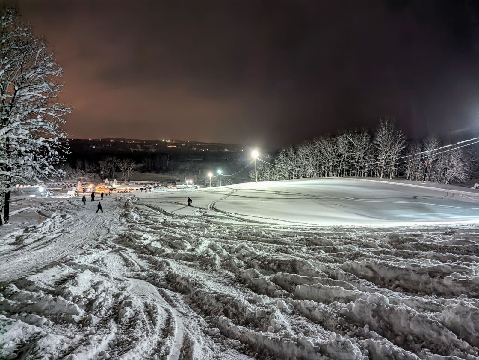 Nighttime ski area lit trails and panoramic snowy hill views