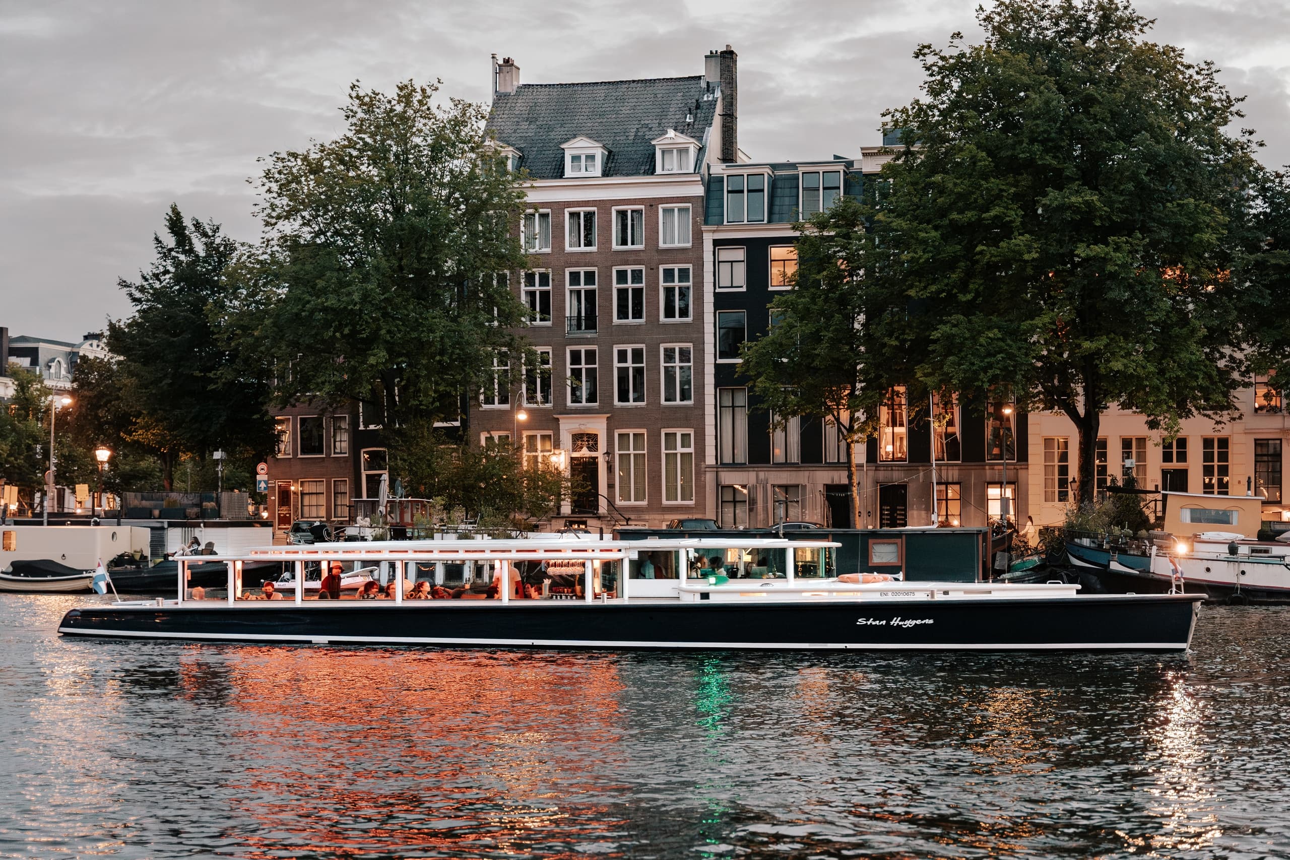 Canal tour boat gliding past historic Amsterdam waterfront buildings