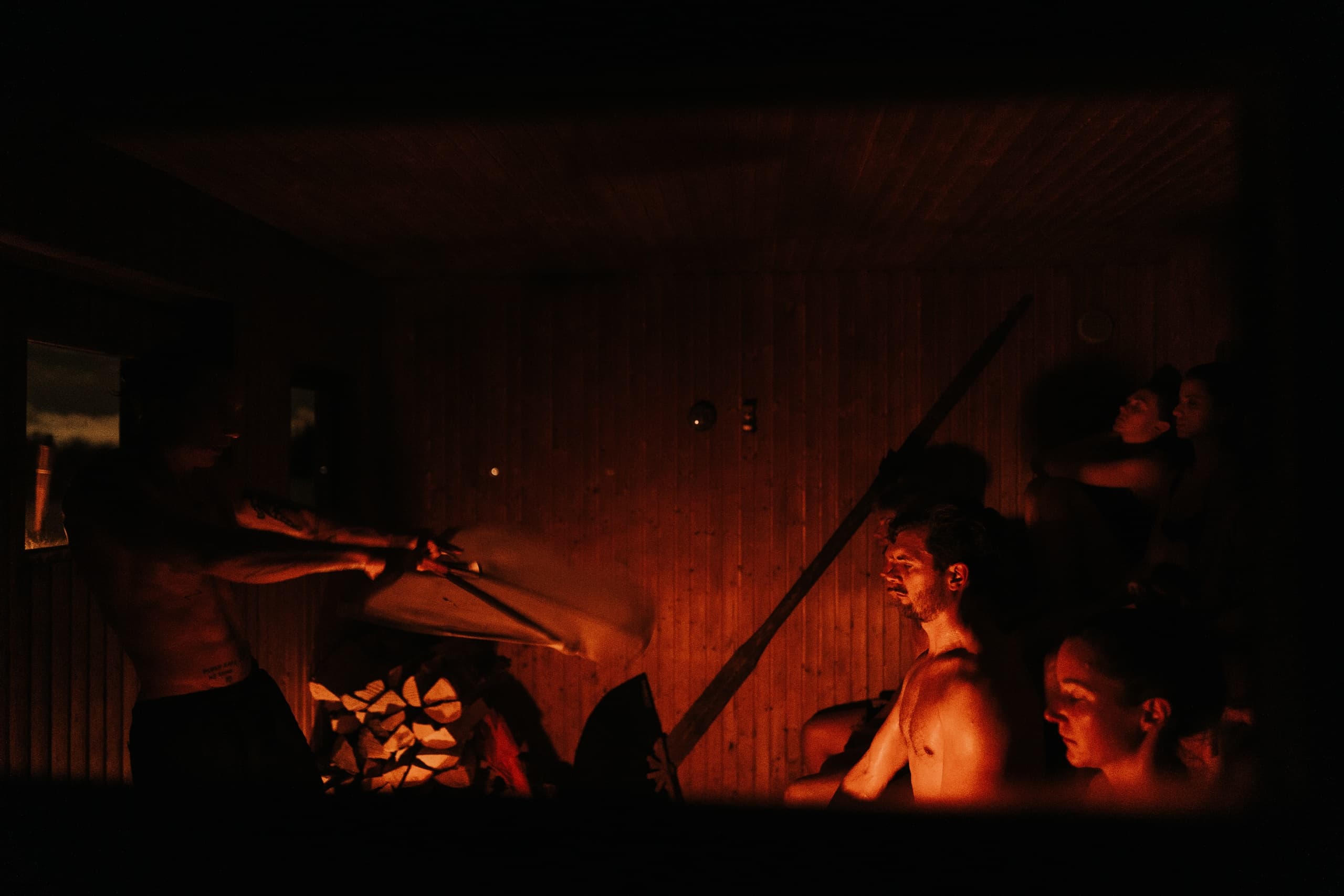 Group in dimly lit sauna cabin enjoying traditional wood-fired heat