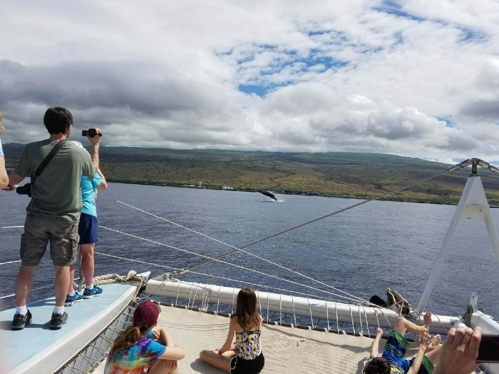 Passengers on boat viewing Hawaiian coastline from catamaran deck