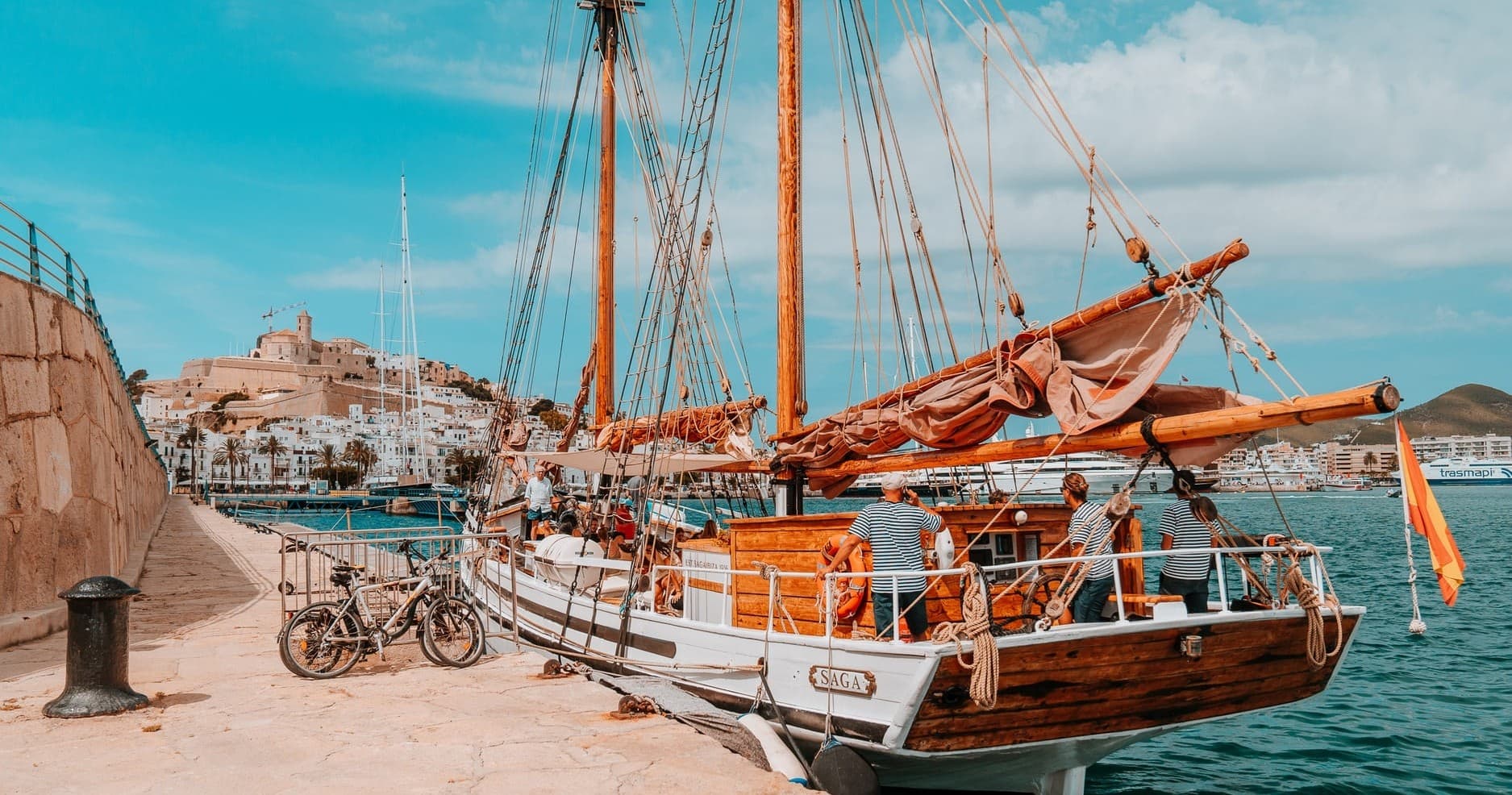 Traditional wooden boat moored at Ibiza harbor with town backdrop