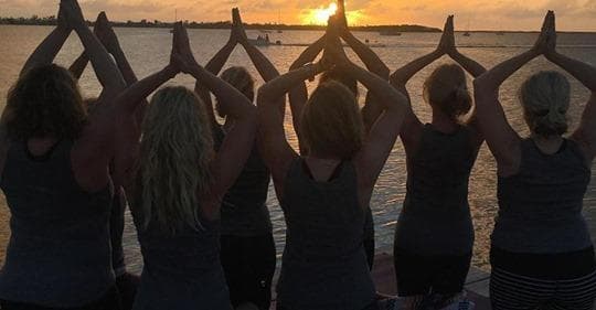 Group sunset beach yoga silhouettes practicing mindfulness