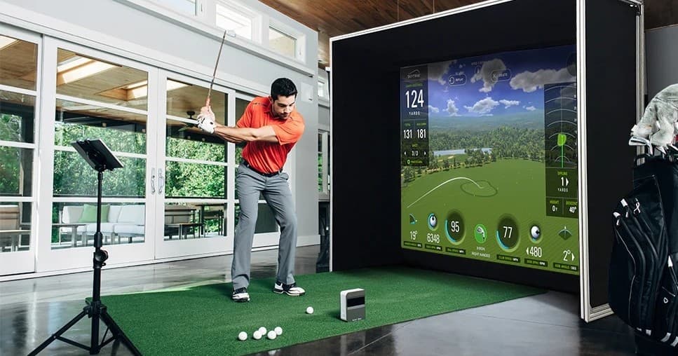Golfer swinging on indoor golf simulator in pub practice bay
