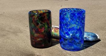 Pair of blown-glass tumblers on sandy beach shore in Hawaii