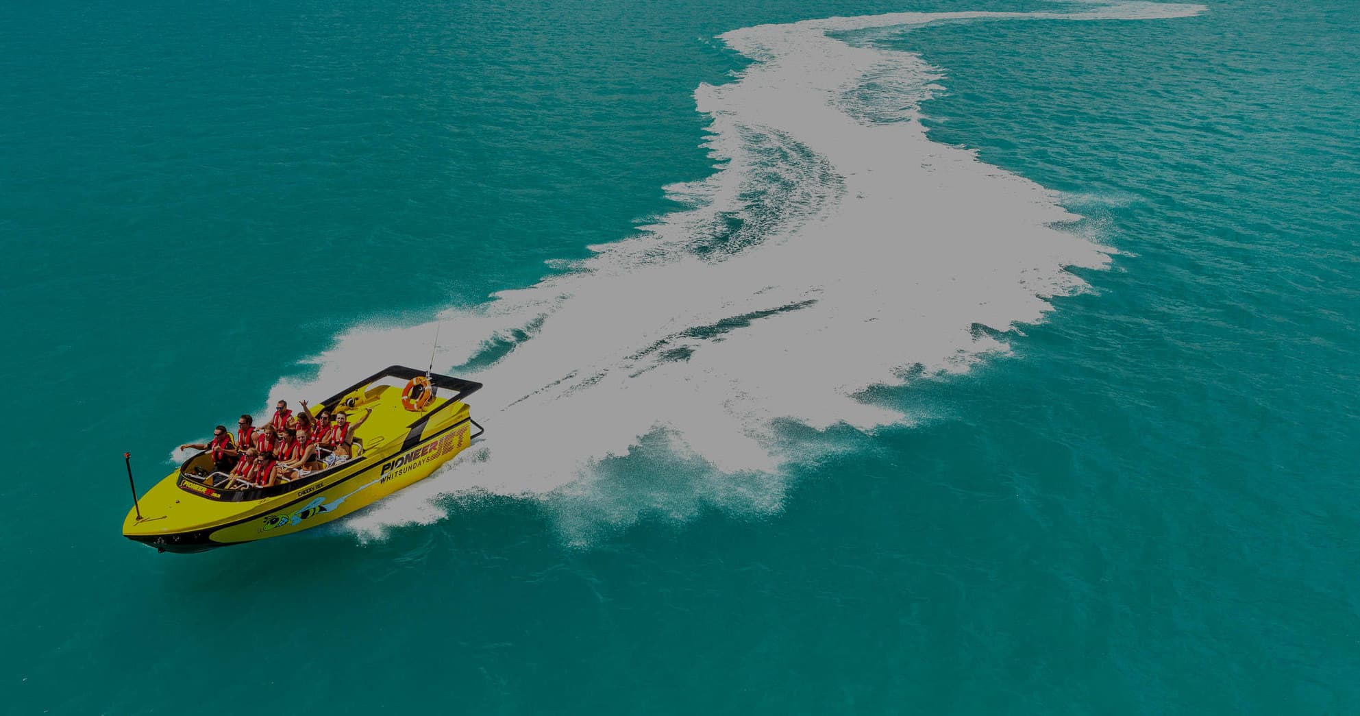 Yellow jet boat carving a dramatic wake across turquoise sea