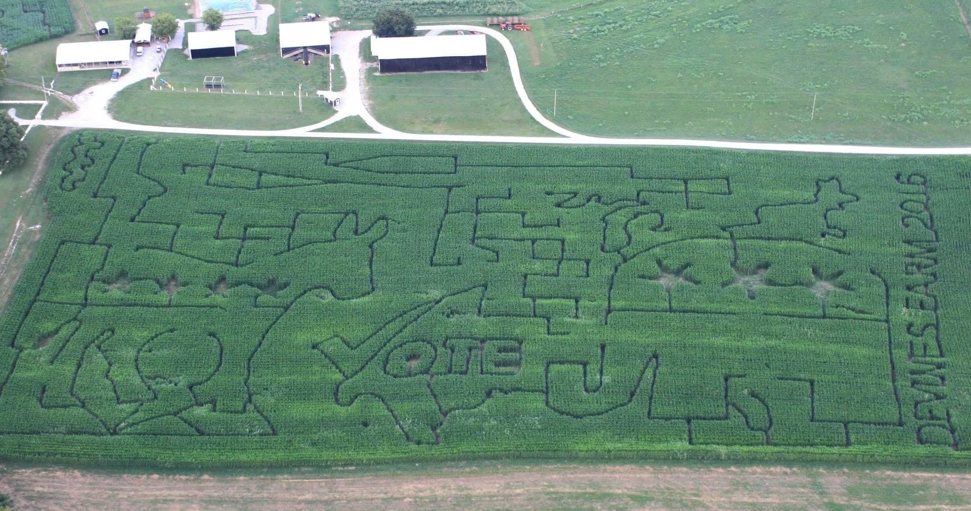 Wide aerial farm corn maze with farm buildings and trails