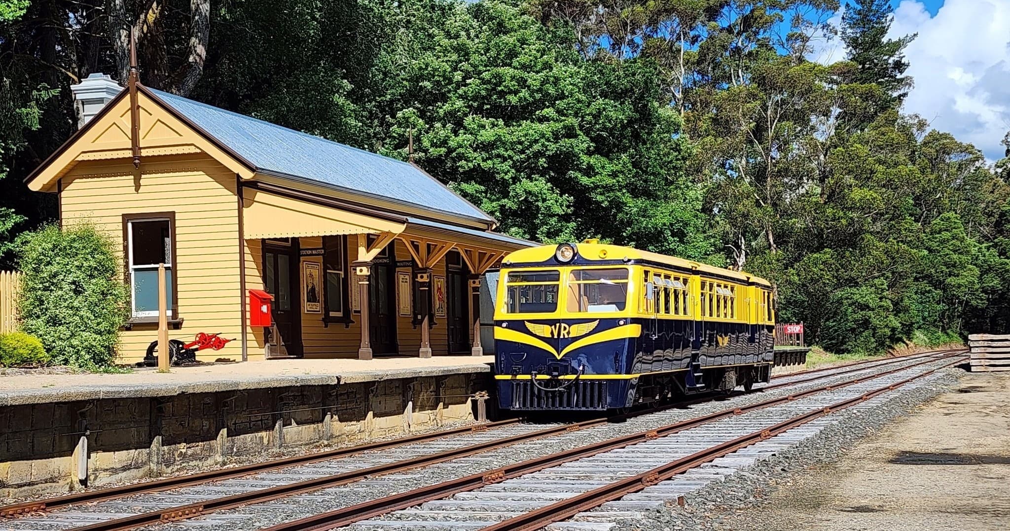 Vintage yellow train at rural station amid forested landscape