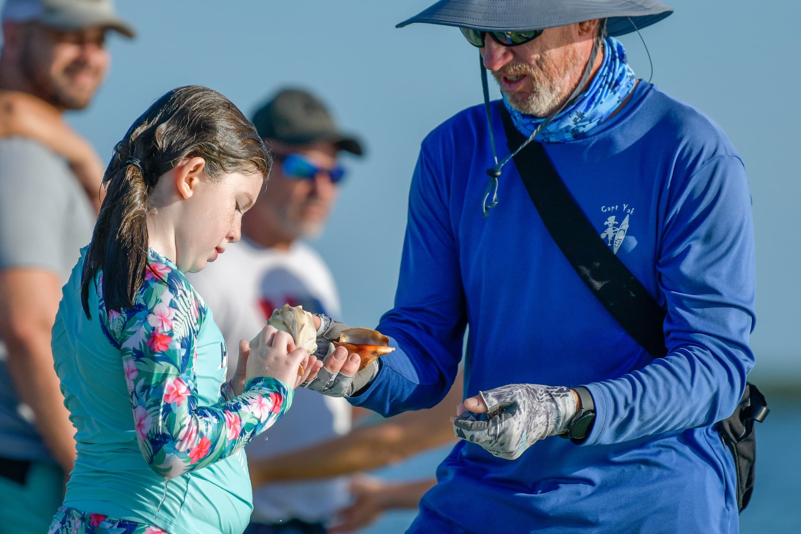 Instructor showing girl a caught fish during coastal fishing lesson