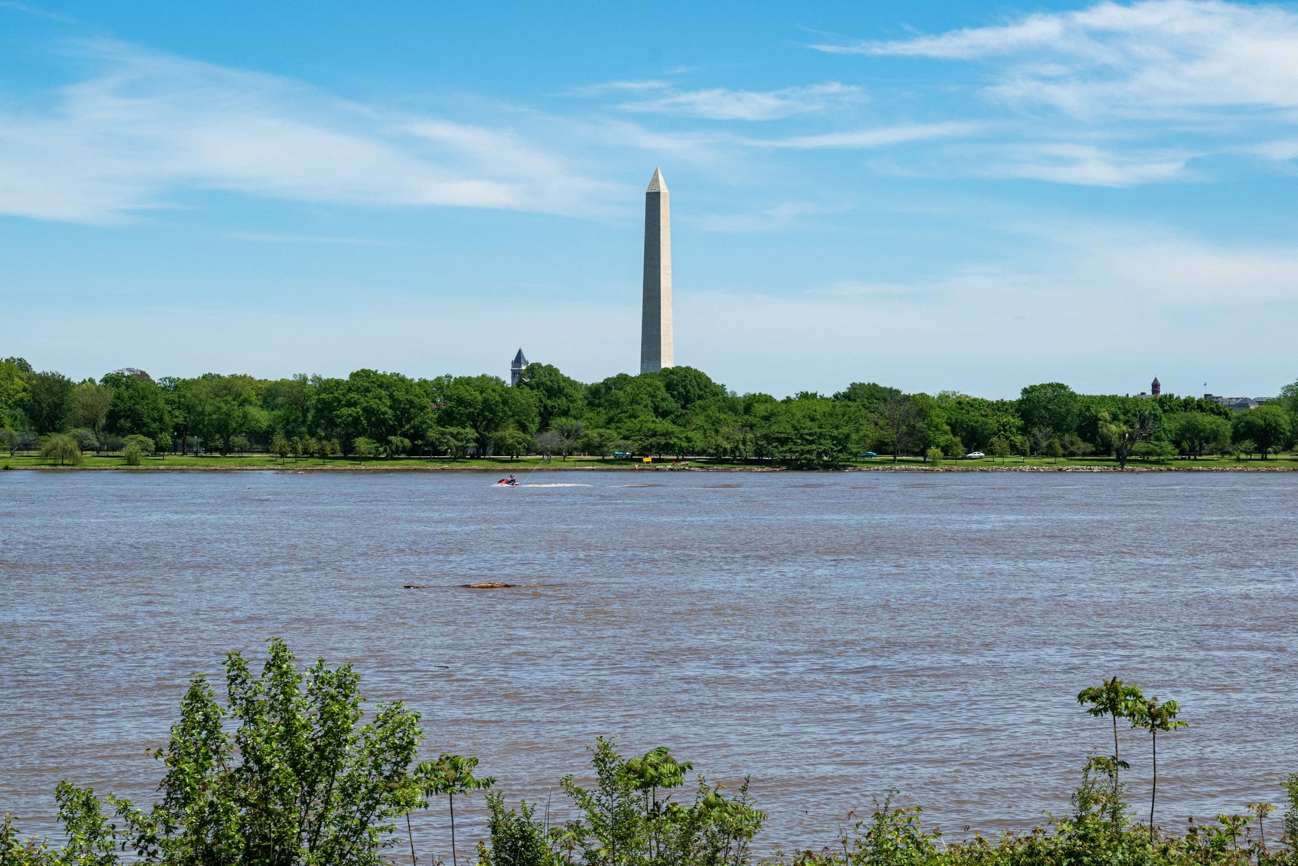 Washington Monument across tidal river with lush shoreline, DC