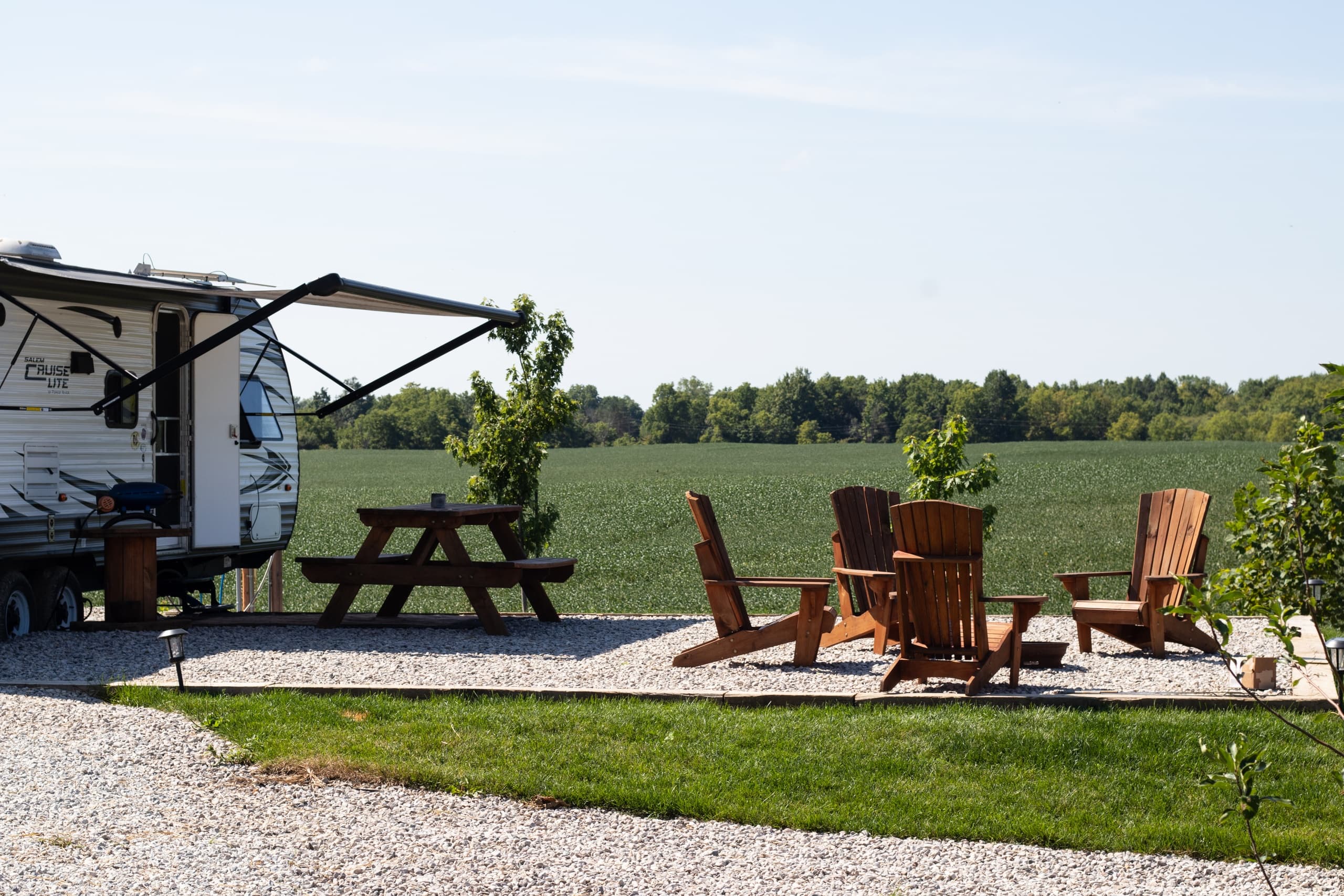 Rural RV campground picnic area with chairs and firepit