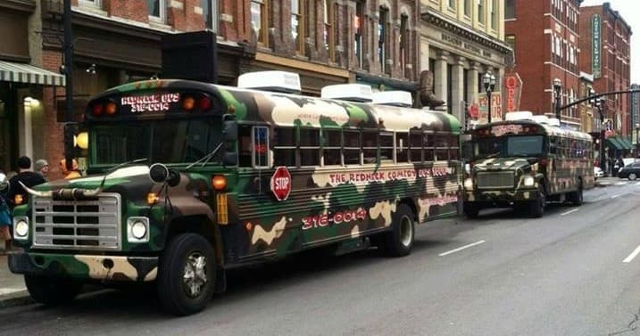 Camouflage tour bus rolling along historic downtown street