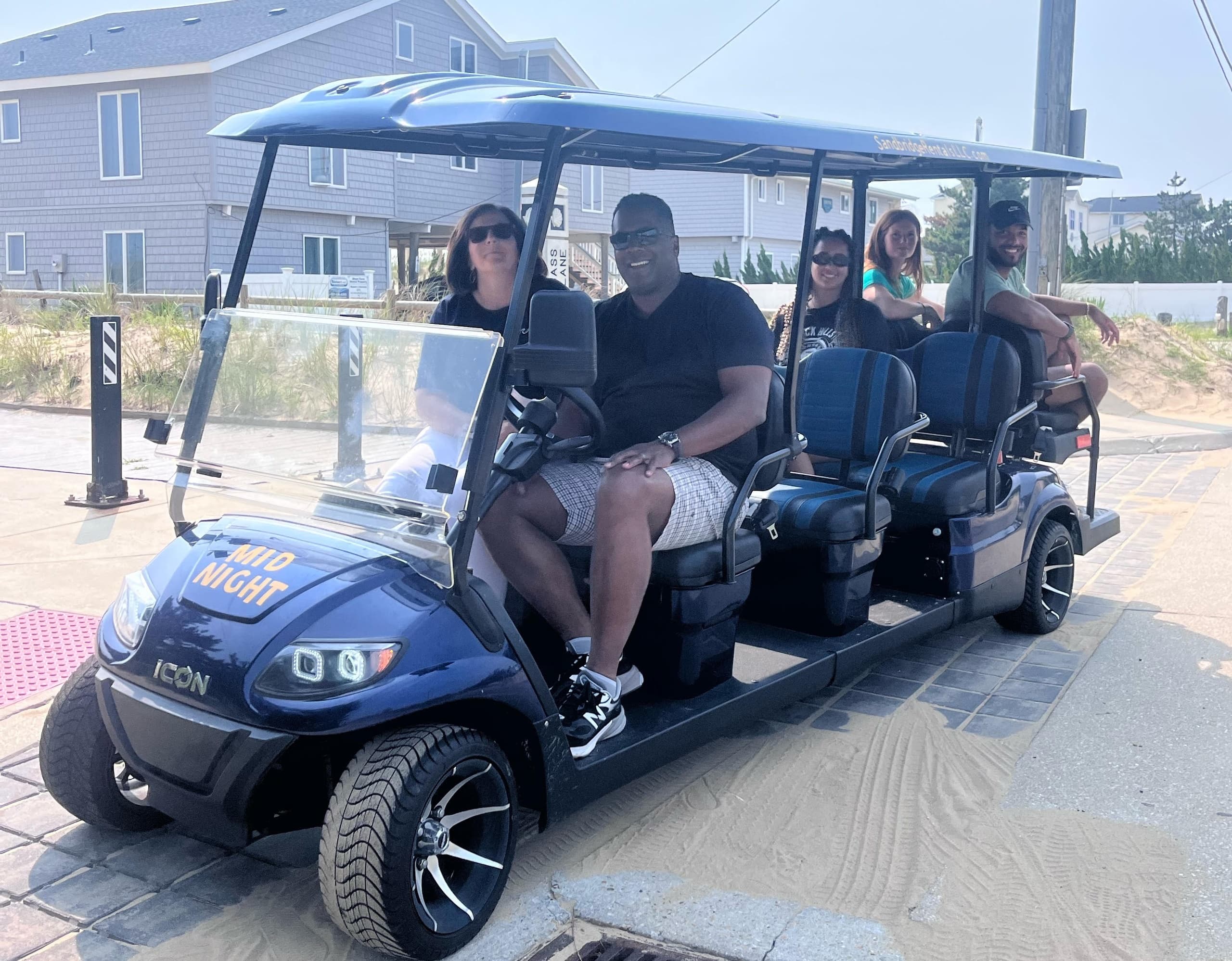 Six-seat golf cart with passengers on beachside boardwalk
