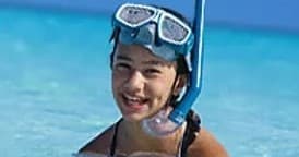 Smiling child snorkeling with mask in clear turquoise waters