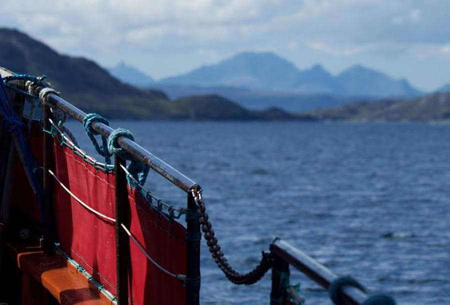 Boat railing with distant mountains over calm sea