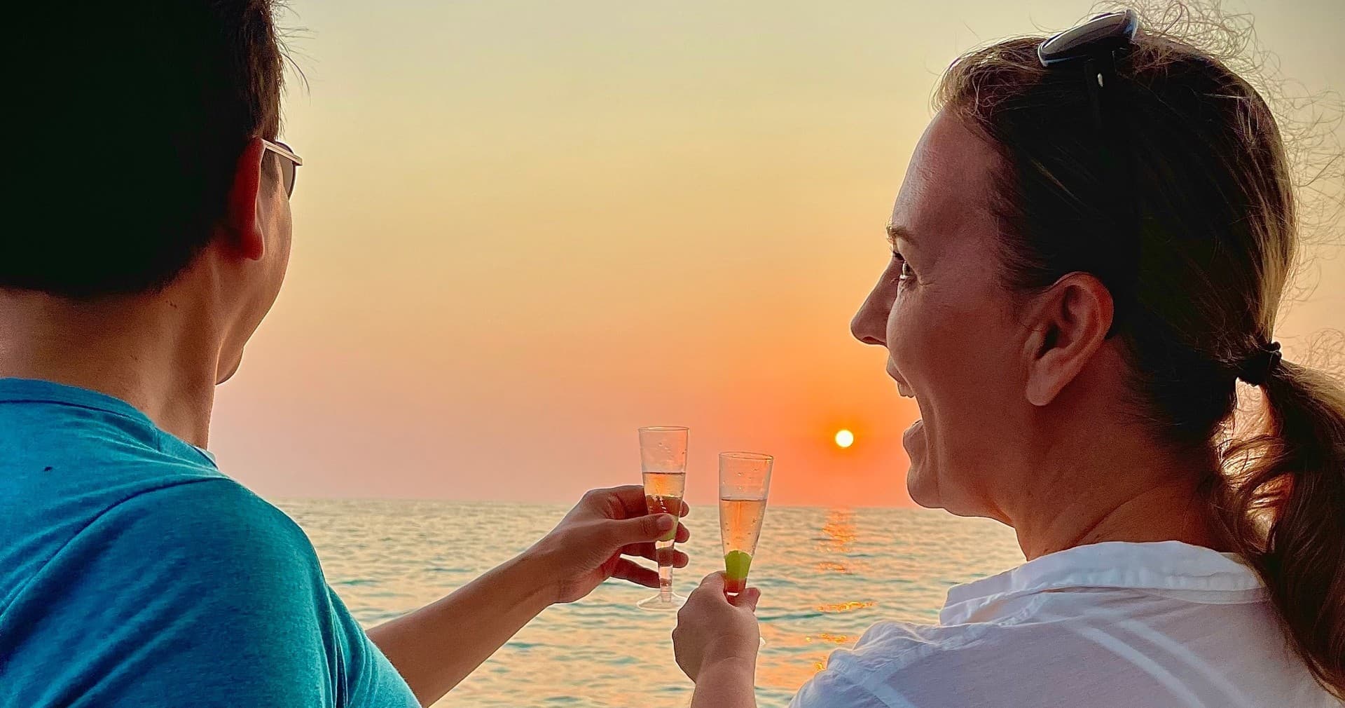 Couple toasting at sunset on yacht watching ocean horizon