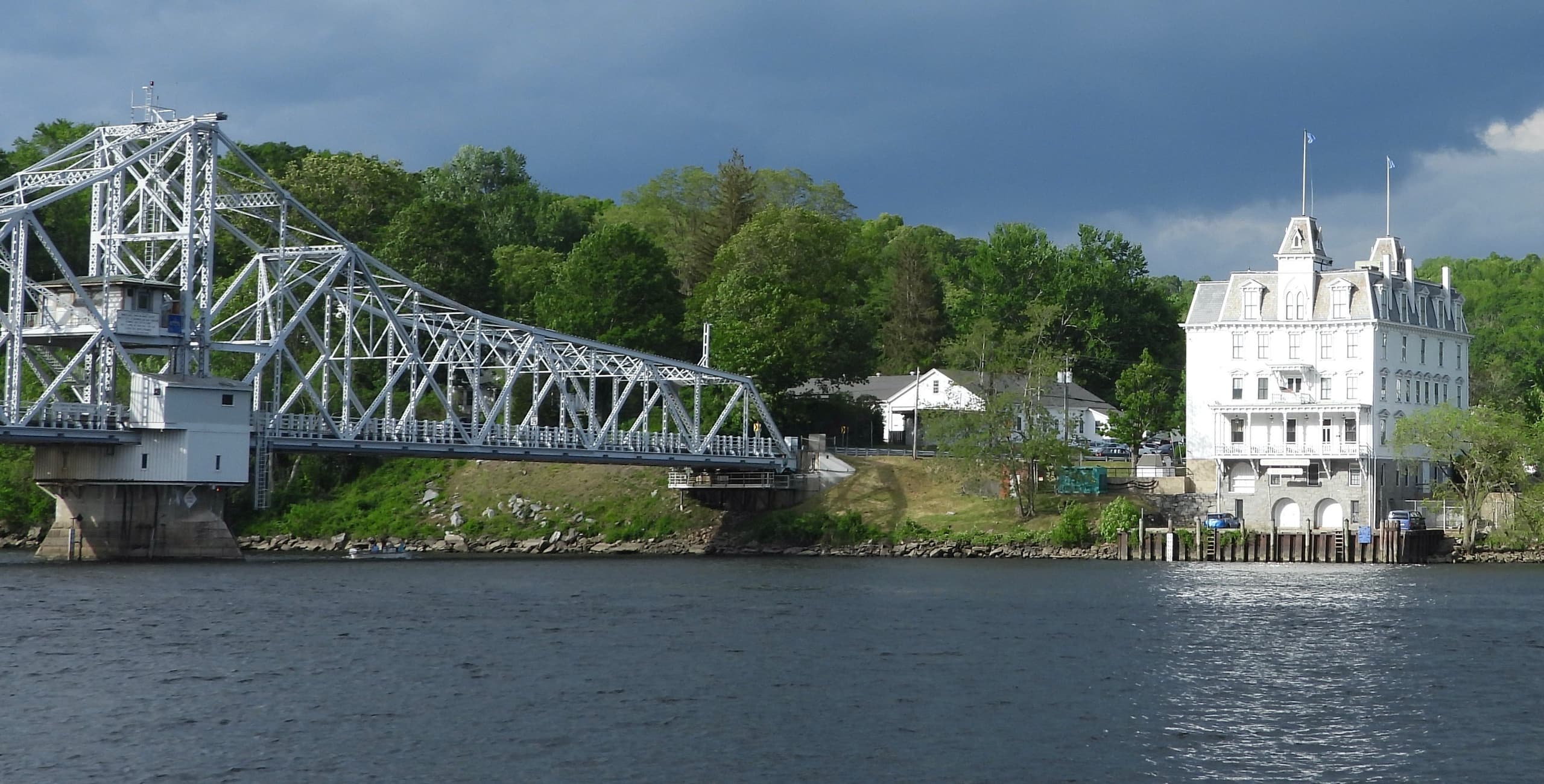 Historic steel bridge spanning river beside waterfront inn