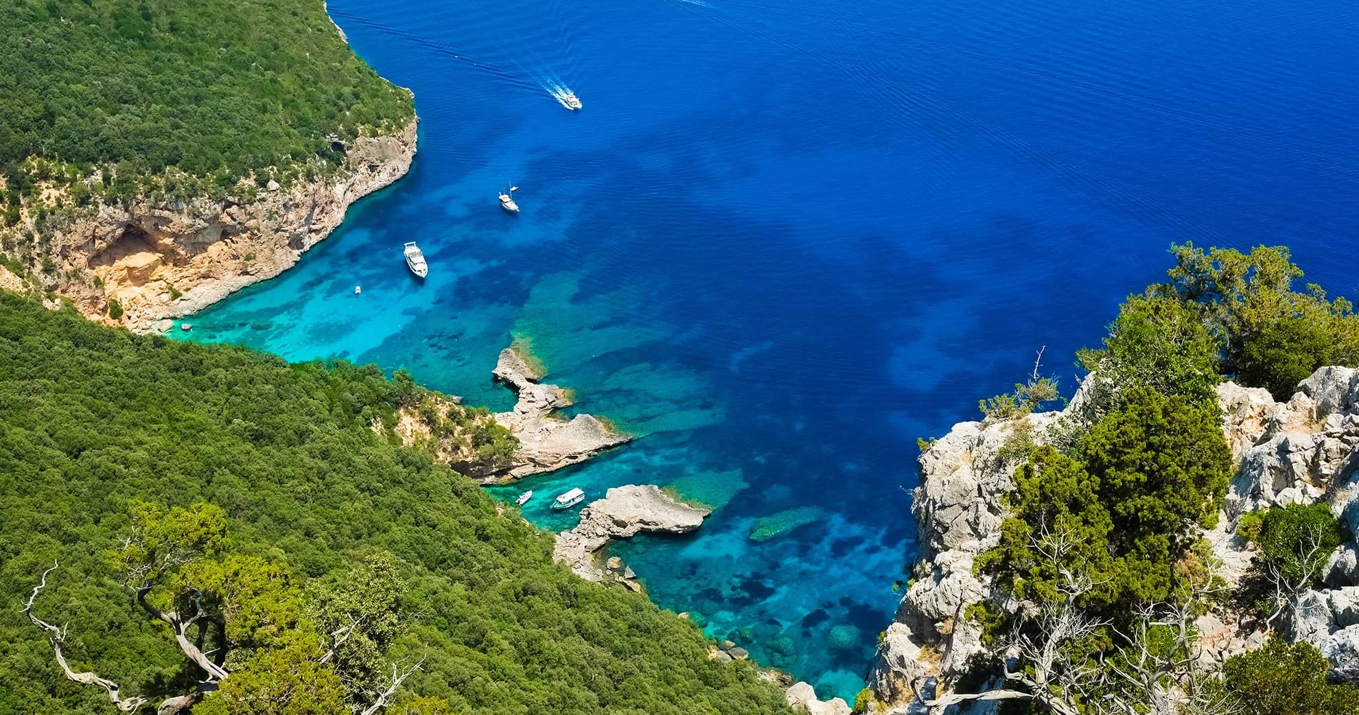 Aerial view of boat in turquoise Mediterranean cove