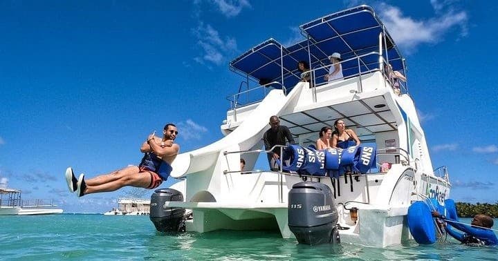 Passengers jumping from boat into tropical turquoise sea on boat excursion